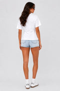 Woman wearing a white t-shirt and light blue denim shorts on a plain background