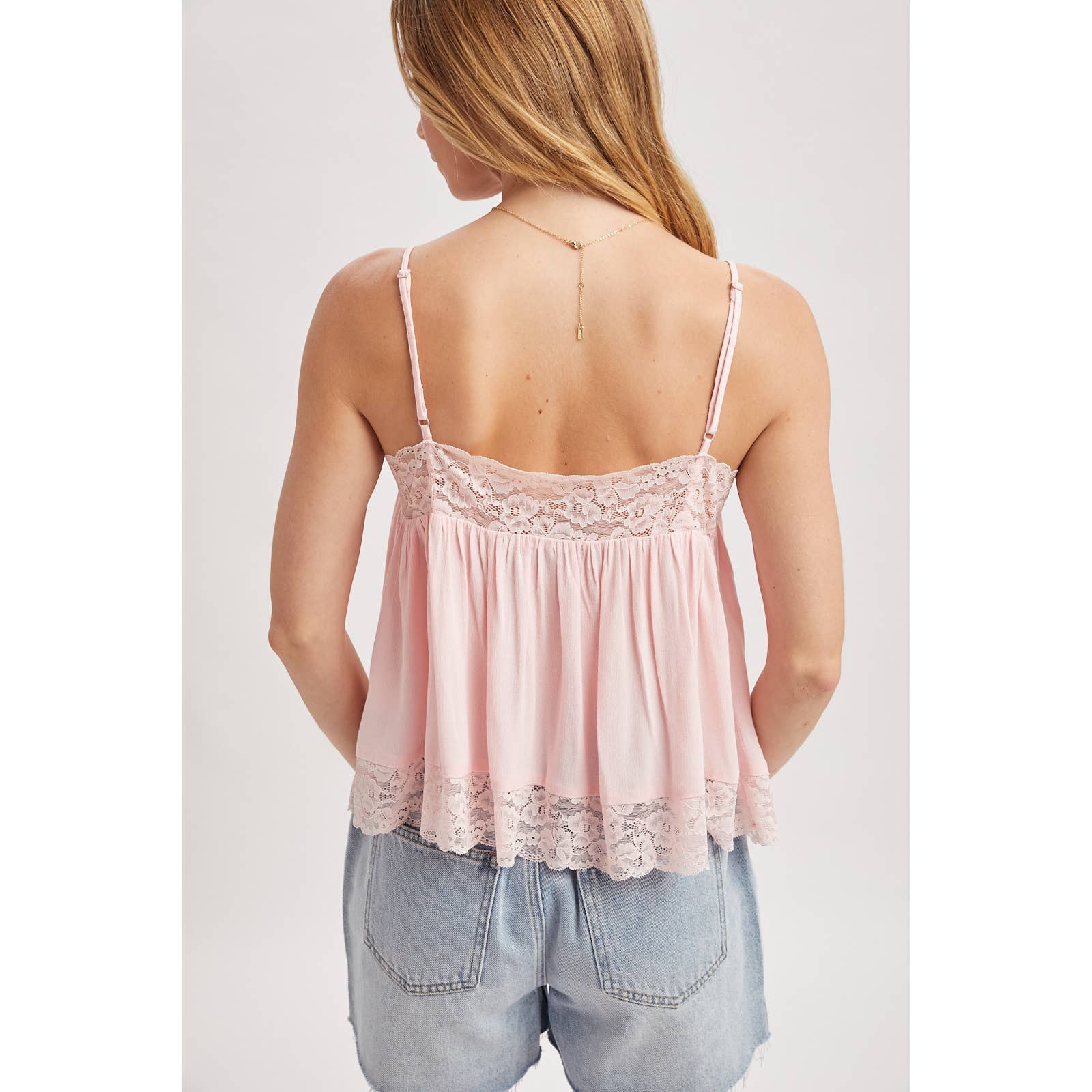 Pink lace-trimmed tank top worn by a person on a white background