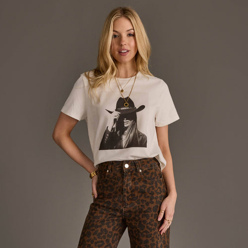 Woman wearing a white t-shirt with a graphic design and leopard print pants on a gray background