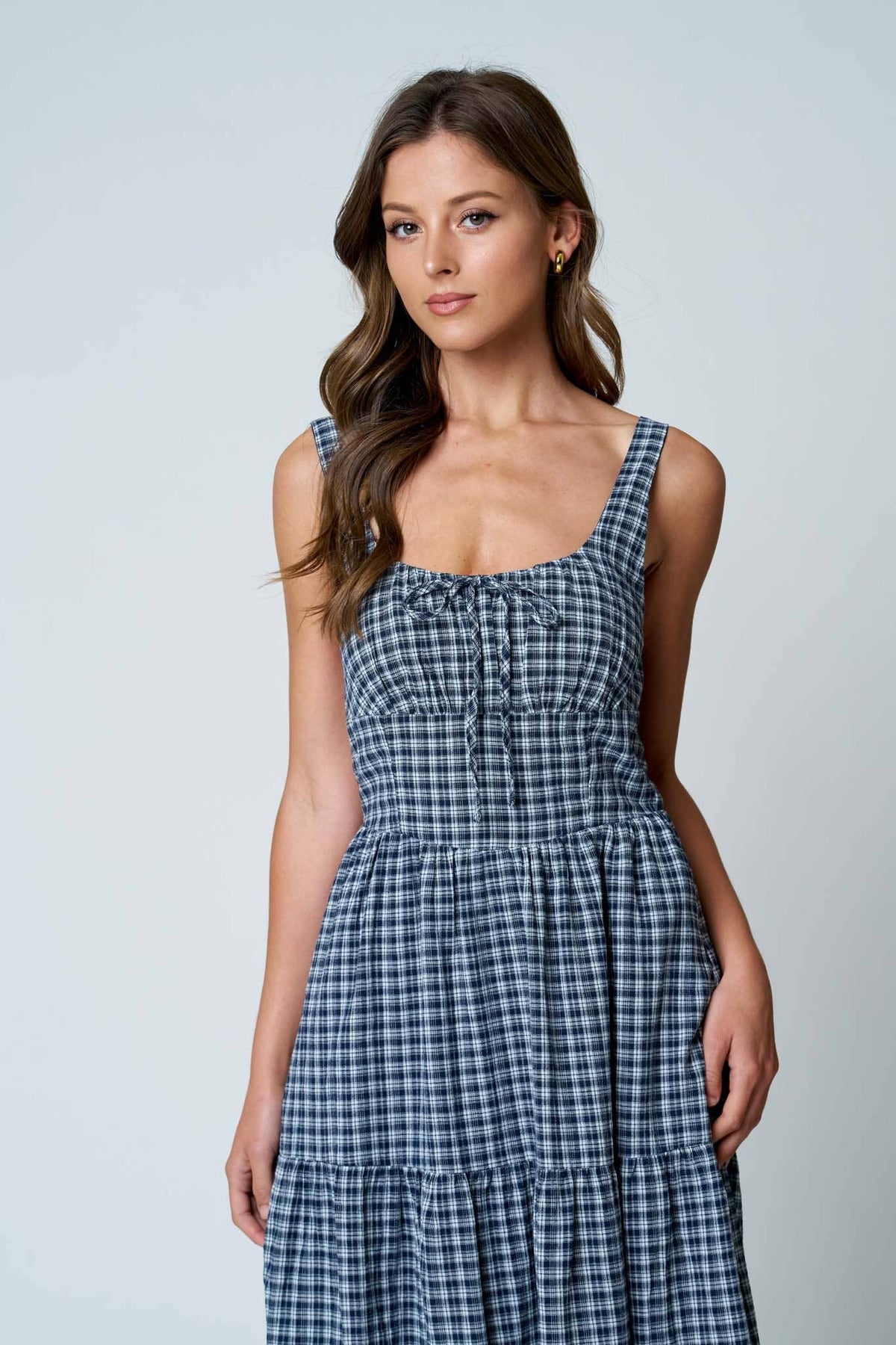 Woman wearing a blue checkered dress against a plain background