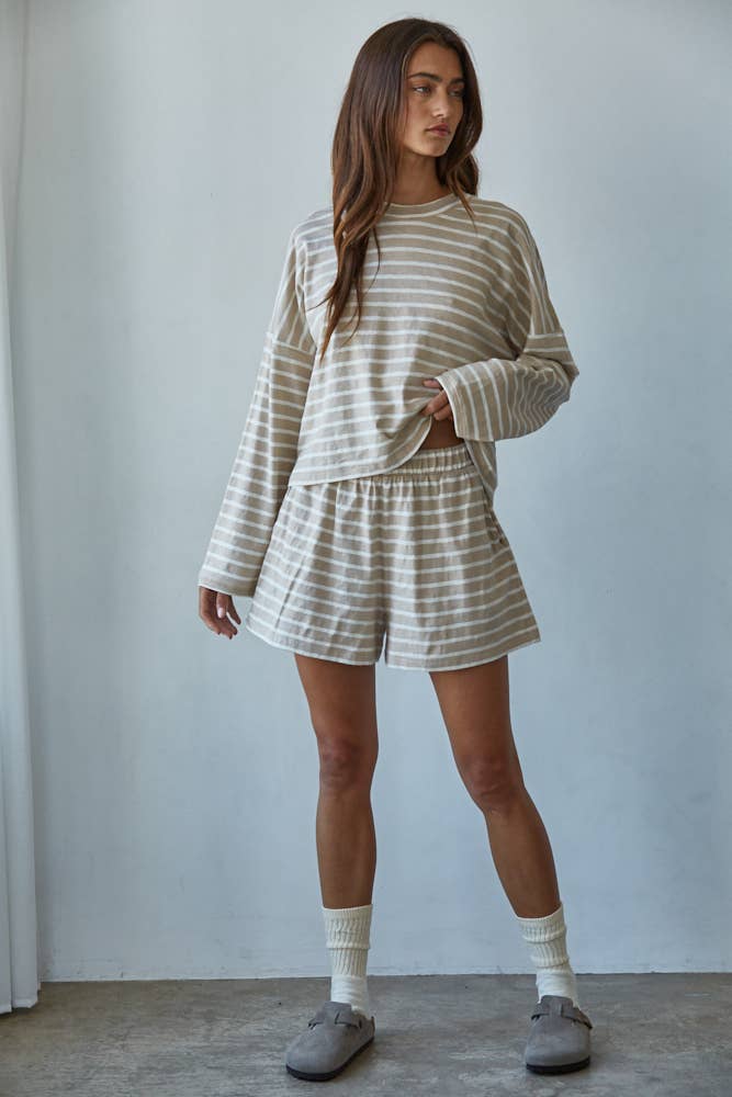 Woman wearing a striped outfit with shorts and a long-sleeve top against a plain background