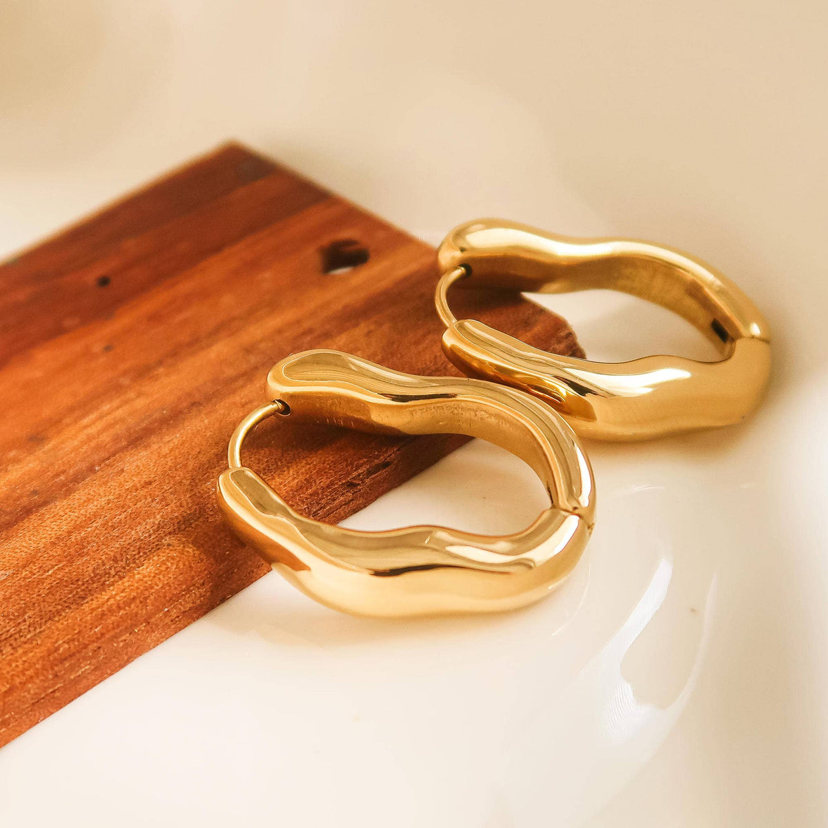 Gold-plated hoop earrings in a chunky sculpted oval shape.