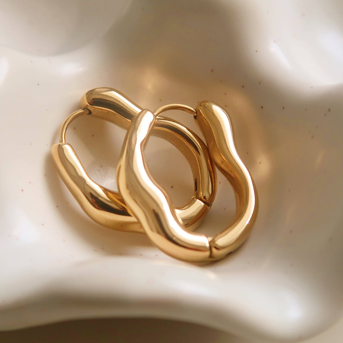 Gold-plated hoop earrings in a chunky sculpted oval shape.