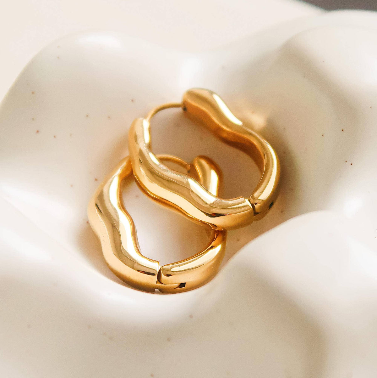 Gold-plated hoop earrings in a chunky sculpted oval shape.