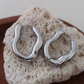 Silver, white gold-plated hoop earrings in a chunky, sculpted oval shape. 