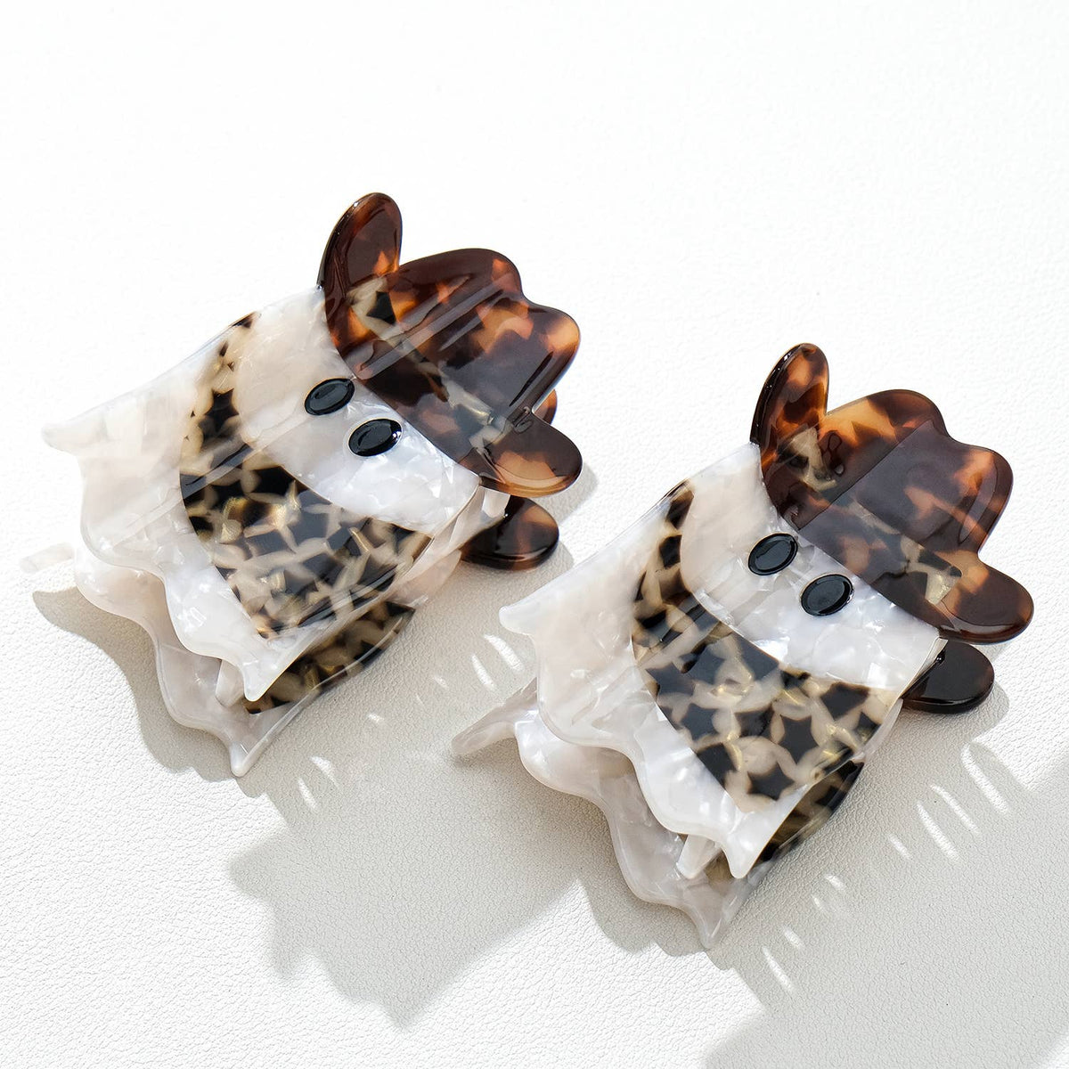Pair of tortoiseshell and white cowboy ghost hair clips on a white background