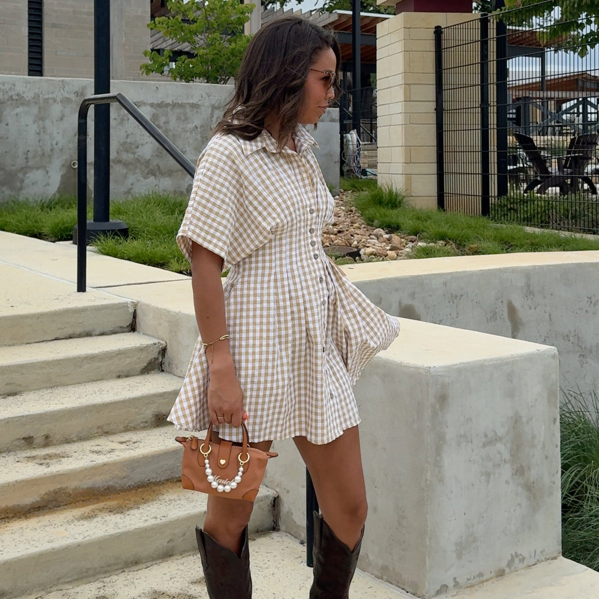 Woman in a plaid dress standing outdoors on a cloudy day