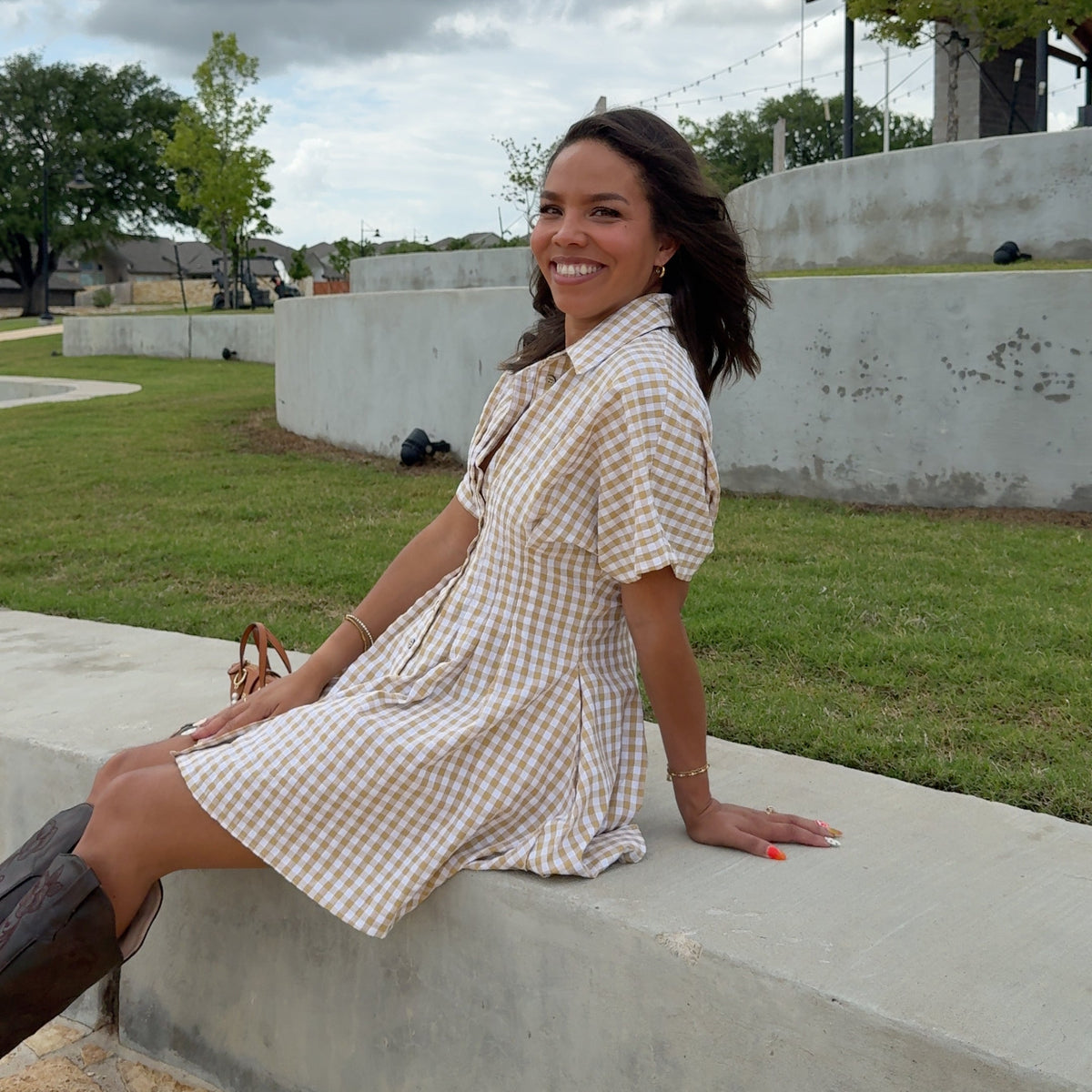 Woman standing on a sidewalk with grass and trees in the background