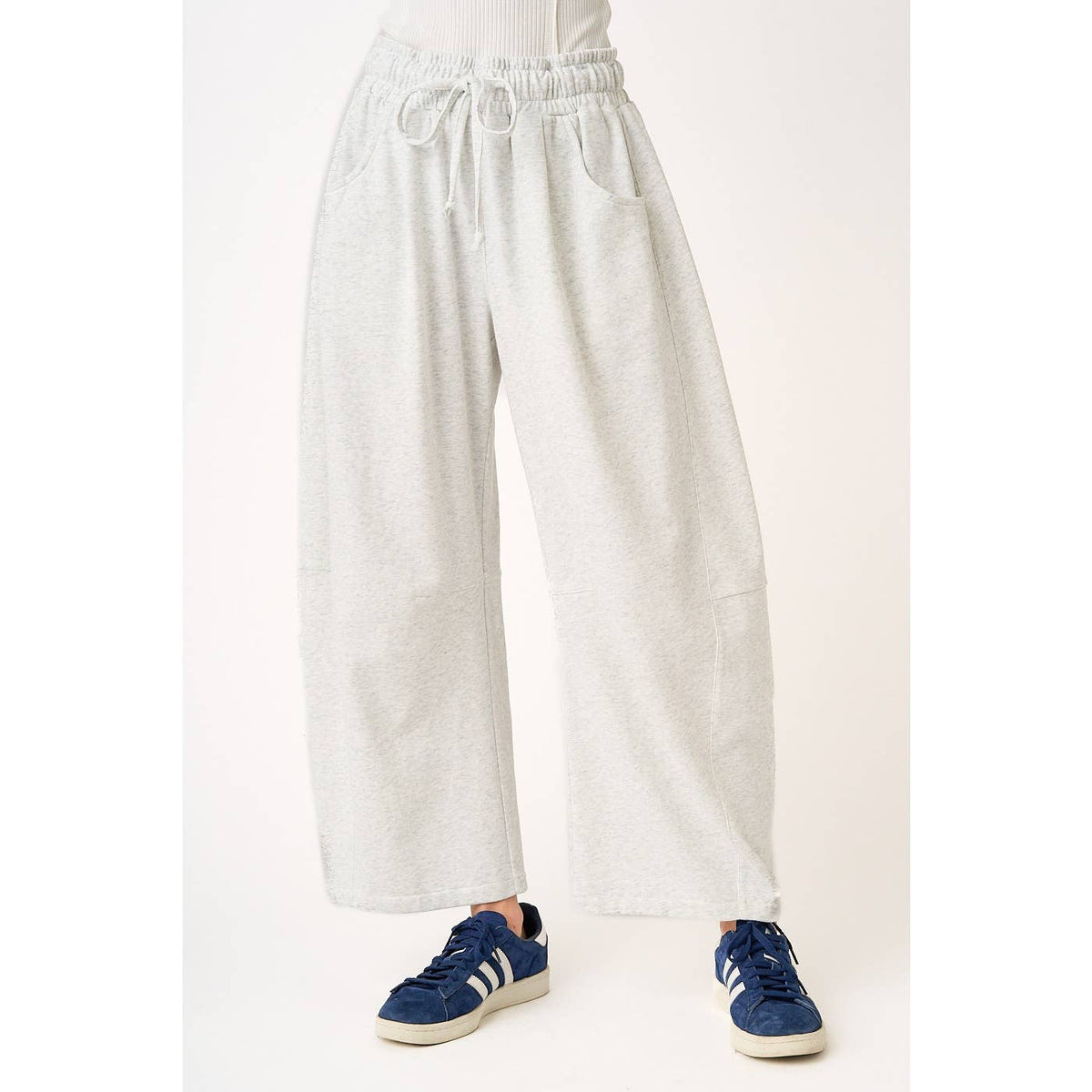 soft and comfortable Light gray barrel sweatpants worn by a person in sneakers on a white background
