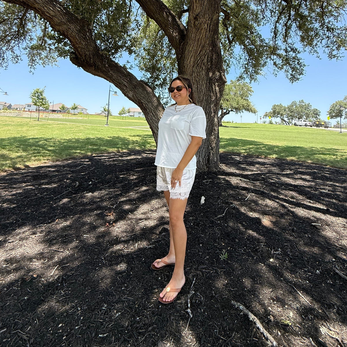 A person wearing a white t-shirt and white satin shorts